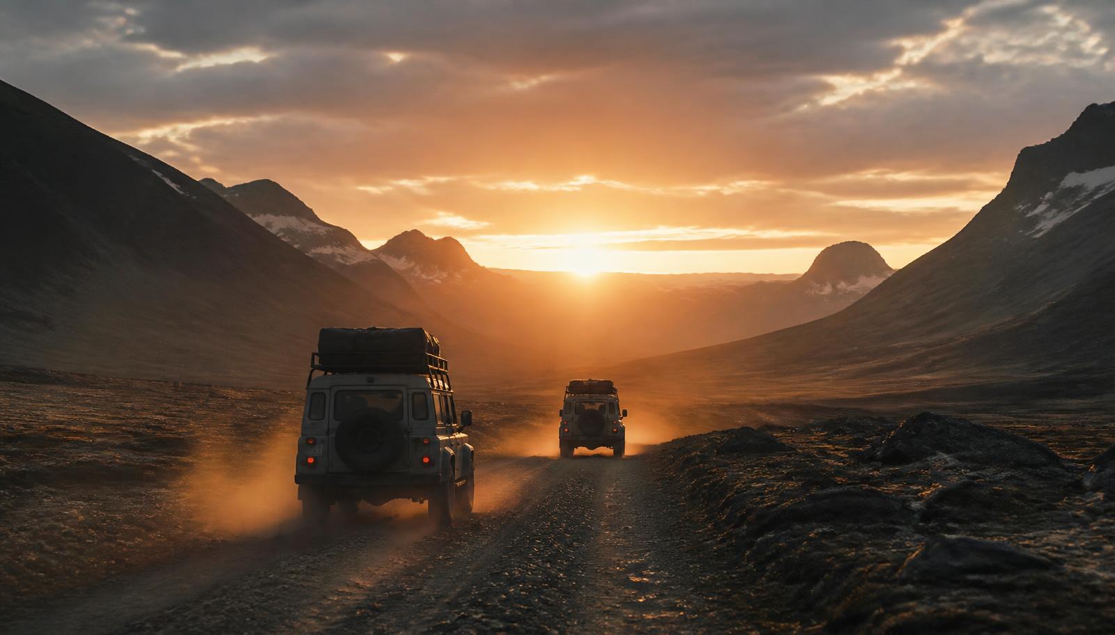 Two expedition 4x4 vehicles driving toward a distant horizon on an empty road